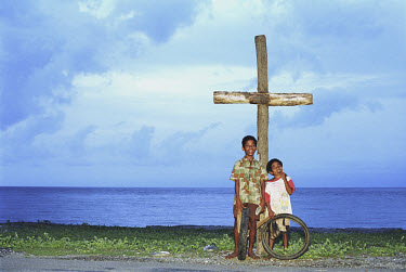 Kids pose next to a cross by the road between Dili and Kupang.