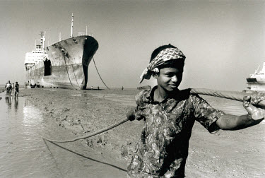 Boy working in the ship-breaking industry, reducing rusting hulks to scrap iron and other reusable materials.