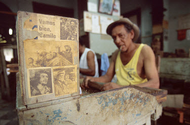 Newspaper cuttings from the days of the revolution decorate a cigar-roller's workbench in a small factory.
