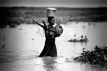Female Sudan People's Liberation Army (SPLA / SPLM) fighter wading through a river.