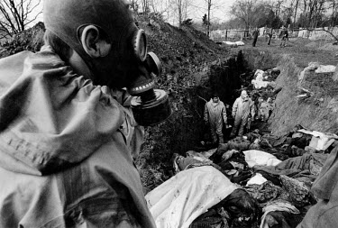 Russian soldiers wearing gas masks examine a mass grave to look for their fallen comrades. Countless unidentified bodies, the majority civilians, were dumped here after the battle for Grozny.