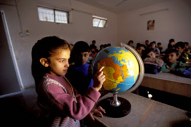 Primary school class. Girl examining a globe.