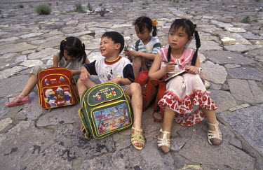 Children sitting near the Yangtze River with Disney bags.