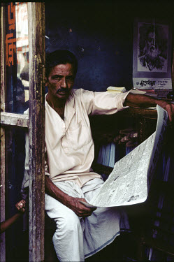 Shopkeeper reading the newspaper.