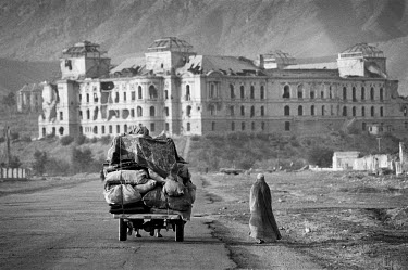 Internally displaced persons (IDPs) fleeing the city as the Taliban take over, taking as many possessions as they can. The damaged former Royal Palace is in the background.