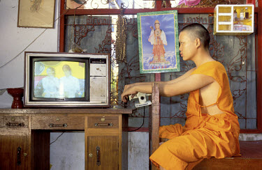 Buddhist monk watching a soap opera on television.
