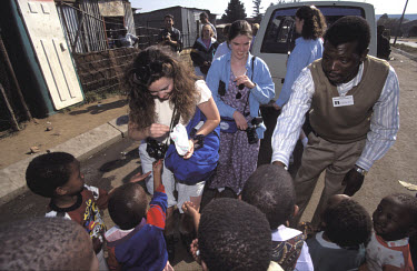 White tourists handing out sweets on a tour of Soweto.
