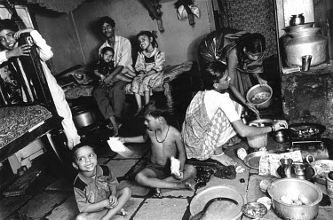 Two sex workers at home, preparing a meal for themselves, their children and a visiting cousin from their village (background). This room also serves as their workplace.