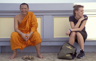 A Buddhist monk shares a seat with a Western tourist at the Wak Saket temple in the old city.