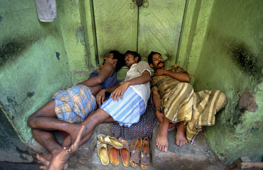 Labourers taking a break, sleeping in doorway.