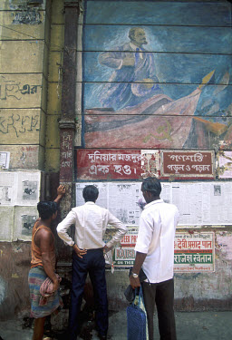 People reading daily newspaper pasted on wall beneath a mural of Lenin: Calcutta has spent much of its post-Independence political life as a Communist city.