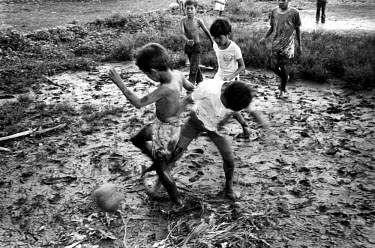 Boys playing football in a paddy field.