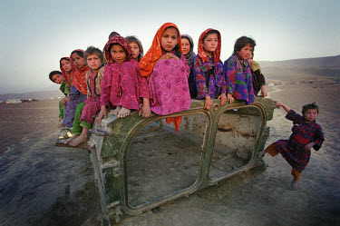 Children in Nawabad refugee camp sitting on a piece of abandoned military hardware. Across Afghanistan, the detritus of war has become a plaything for generations of children.