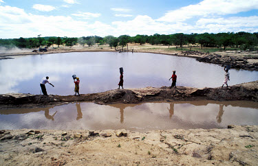 Tonga community building a dam.  Women doing all the heavy work while the only man tells them what to do.