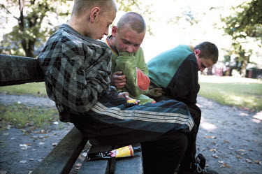 Three street children sitting in a park sniffing glue. There are approximately 10,000 street children in Riga. Most of their parents are either in gaol, alcoholic or dead.