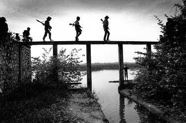 Soldiers from the government army cross the remains of a dam, built in the 1970s by the Khmer Rouge.