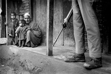 A father crouches with his two children in the shadow of a soldier from the Indian security forces. Up to 500,000 Indian troops are posted in Kashmir, with many people seeing them as an occupying army...