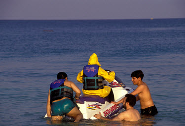 A family jetskiing off a mixed beach - the woman has to remain fully clothed.