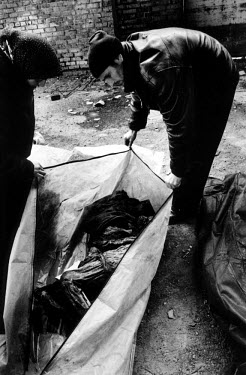 Chechen civilians searching for missing relatives unzip bodybags holding unidentified remains found in a mass grave. In February 2001 Russia authorities disclosed the location of the grave in the grou...