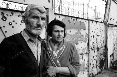 Raya and Astimir, a teacher and engineer, stand in front of the shrapnel-marked entrance to their house. They are looking for their only child, Zelimhan, 19, who eye-witnesses say was beaten and dragg...