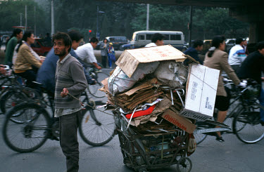 Migrant with a cart-load of cardboard collected to sell for recycling.