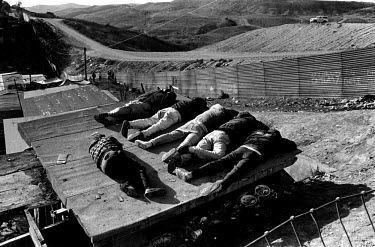 Migrants sleeping beside the fence which marks the American-Mexican border. Since a clampdown by the border patrols (visible top right), many people have been left in limbo on the Mexican side, unable...