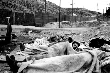 Migrants sleeping beside the fence which marks the American-Mexican border. Since a clampdown by the border patrols, many people have been left in limbo on the Mexican side, unable to carry on or to r...