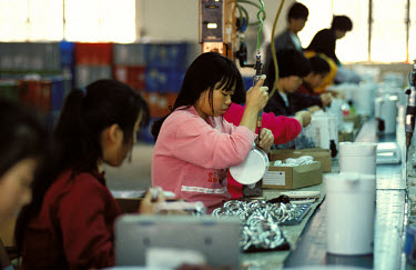 Migrant worker on a factory production line producing kettles for export.