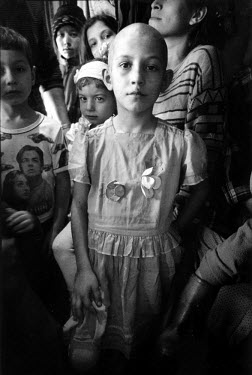 A young Chechen girl stands in the crowded hallway of a train wagon that has been her home for over two years. Her family, like thousands of others, are refugees fleeing war in Chechnya. Her mother ha...