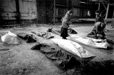 A woman searching for missing relatives unzips bodybags holding the remains of unidentified people from a mass grave. In February 2001 Russian authorities disclosed the location of the grave in the gr...