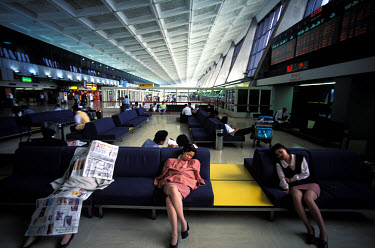 Departure lounge at Chiang Kai-shek international airport. One woman covers herself in newspapers to help her sleep.