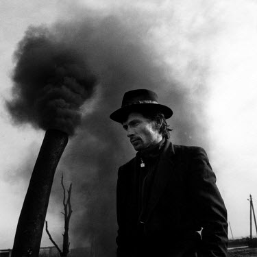A Chechen man stands near the smokestack of a small-scale factory producing benzene. Local people have built their own mini-refineries to tap oil from the ground or from pipelines. Over the past eight...