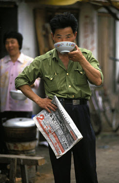 Man drinking tea and reading the newspaper.