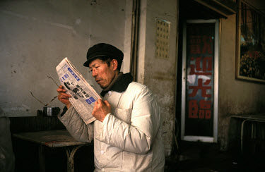Zhengzhou. Man reading a newspaper in cheap restaurant.