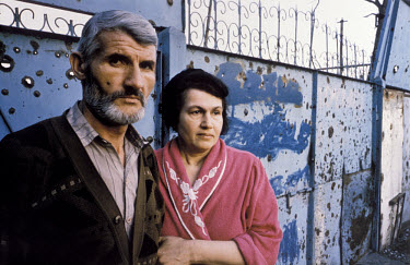 Raya and Astimir, a teacher and engineer, stand in front of the shrapnel-marked entrance to their house. They are looking for their only child, Zelimhan, 19, who eye-witnesses say was beaten and dragg...