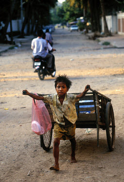 Young boy collecting plastic and metal on the street to re-use or sell.