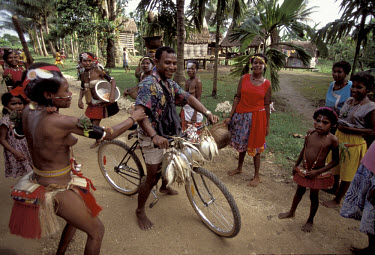 Women stop and joke with a cyclist during the yam harvest festival in Kiriwina.