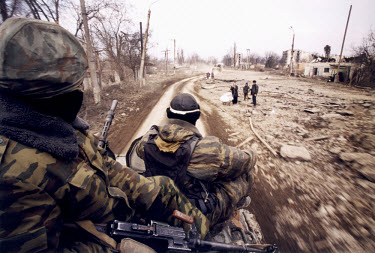 A Russian special forces unit on an armoured personnel carrier drive through the flattened remains of war-torn and bombed central Grozny. Civilians on the roadside stay clear of the tanks and APCs. Wo...