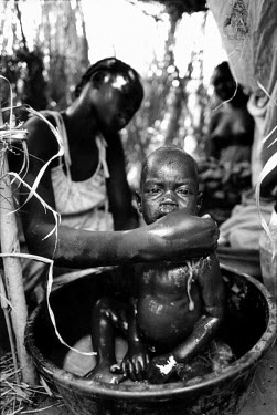 A mother washes her baby in a makeshift IDP camp in Parajok, near Torit. 70,000 people fled here after government bombing raids of the well-provisioned camps at Ame and Atepi. The new camp, a week's w...