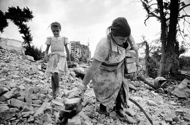 A Chechen mother and daughter spend the day salvaging bricks from the rubble of bombed buildings in the city centre. They will sell the bricks for money to buy food and will also use some to repair th...