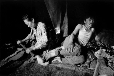 Tanya and her husband, Sasha, sit together on the tundra grass in their choom, a tepee-like shelter. Tanya softens reindeer hides while Sasha relaxes after a long day herding deer. The Nenet people de...