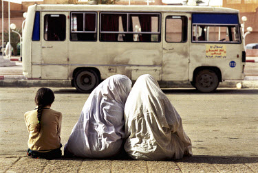 Two women in traditional dress wait with a child at the bus station in Ghardaa. Most of the inhabitants of Ghardaa are Mozabites, a Berber tribe known for their entrepreneurial spirit.