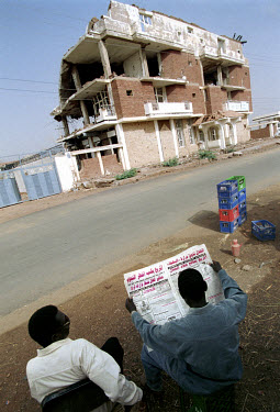 People reading a newspaper opposite the remains of the El Shifa pharmaceutical factory which was bombed in 1998 by the USA in retaliation for the bombing of the US embassies in Kenya and Tanzania. The...