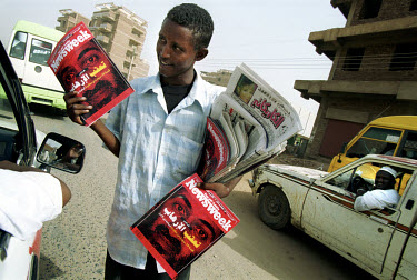 Boy selling newspapers and the Arabic edition of Newsweek magazine on the street in the Sudanese capital. The Newsweek cover carries a portrait of Osama Bin Laden.