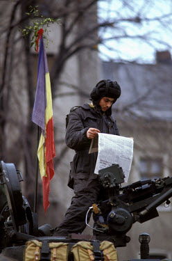 A soldier stands atop his tank reading about the revolution in a newspaper. The Romanian popular revolt and coup of 22nd-25th December 1989 represented a decisive moment in the collapse of communism i...