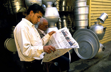 Metalwork sellers reading morning newspapers at their shop in the Islamic City on Bayn al-Qasryn rd.