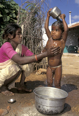 Mother bathing her child by the village water pump in Kullampatti.