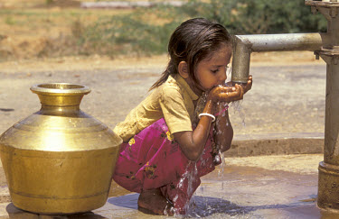 Child taking a drink from a the village handpump, newly installed by the NGO Wateraid.