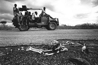 Teenage fighters drive past the skeleton of a famine victim lying by the roadside. In 1991 President Barre was overthrown by opposing clans, but they failed to agree on a replacement and plunged the c...