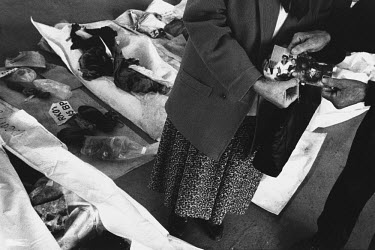A Bosnian Muslim woman tries to find the remains of her sons in a temporary morgue for 250 bodies. A relative holds their photographs in the foreground. These people were killed at the beginning of th...